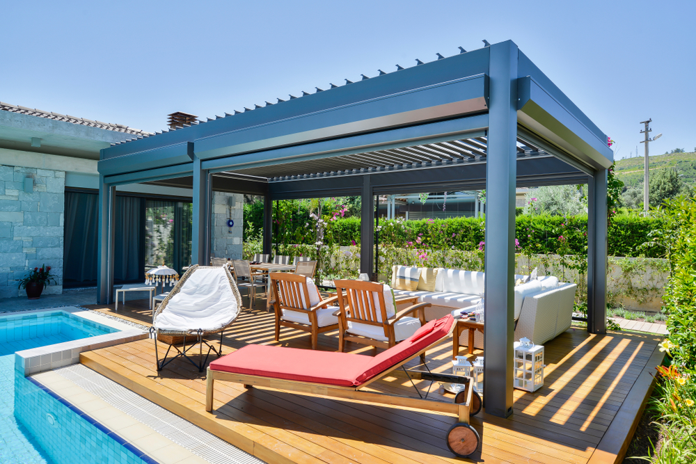 a deck with a pergola and inviting seating next to a pool in the backyard